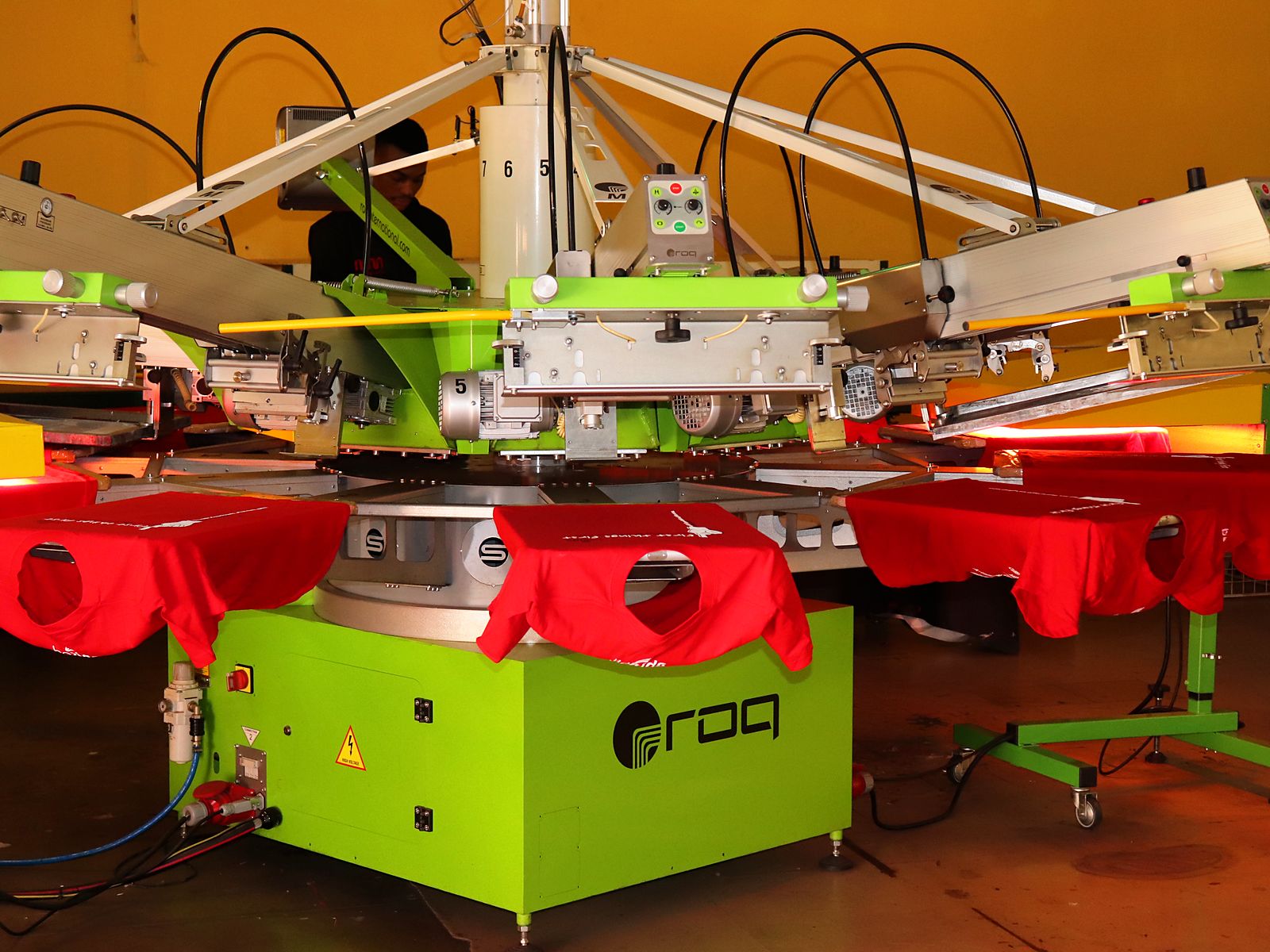 Green ROQ automatic carousel screen-printing press with red tees on the pallets